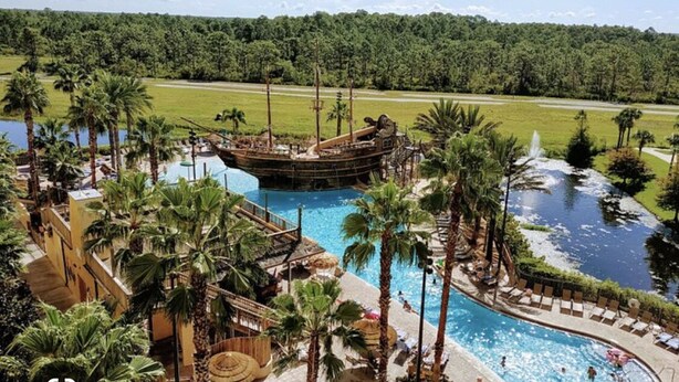Un complexe hôtelier doté d’une grande piscine, de palmiers et d’un bateau de pirates.