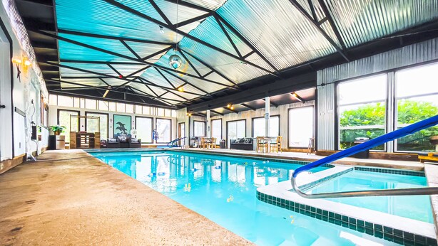 An indoor swimming pool with a tiled edge, a blue slide, and a ceiling with a metal framework. - Exclusive Cottage & Coastal Farmhouse Private Indoor Heated Pool ocean views. (Smith River)