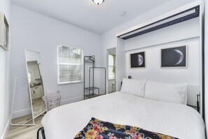 Un dormitorio con una cama grande, un armario, un espejo y dos cuadros en la pared.