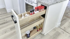 A kitchen with a white stove, granite countertop, and a wooden spice rack with various containers. - Modern Studio - North Oak Park/UC Med Center (Sacramento)