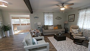 A living room with a sofa, armchair, and a recliner. There is a coffee table, a lamp, and a decorative wall clock. - 🐋Come enjoy paradise with us and bring the family🐾🌊 (Foley)
