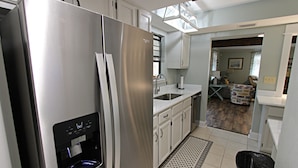 A modern kitchen with stainless steel appliances, white cabinetry, and a water dispenser. - 🐋Come enjoy paradise with us and bring the family🐾🌊 (Foley)