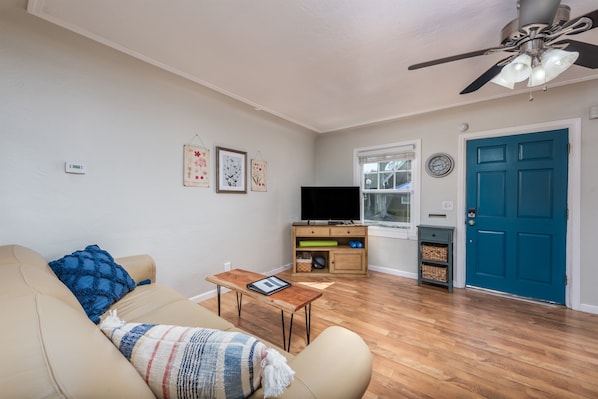 Una sala de estar con sofá, mesa de centro, mueble para televisión y una puerta azul.