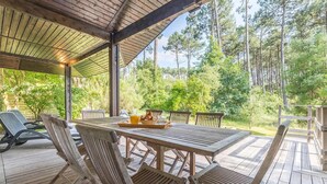 Eine Holzterrasse mit Tisch und Stühlen, umgeben von Bäumen.