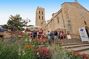 A historic building with a tower, steps leading up to it, and a flower garden in the foreground.