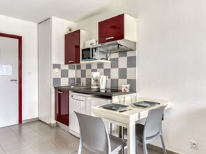 A compact kitchen with a microwave, coffee maker, and a small dining table with two chairs.