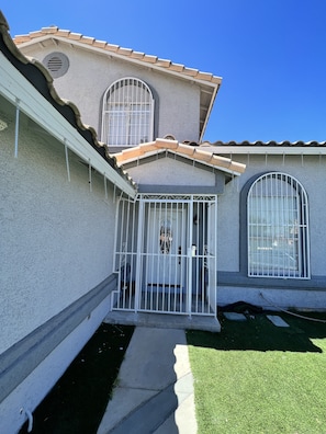 A house with a gated entrance, a small porch, and a window with a metal grill.