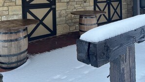 A building with stone walls and black-framed doors, wooden barrels, and a snow-covered ground.