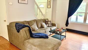 Un salon avec un canapé beige, une table basse et une fenêtre avec un rideau.
