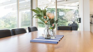 Une table à manger avec un set de table à rayures bleues et blanches, deux vases en verre transparent ornés de fleurs et des chaises noires.