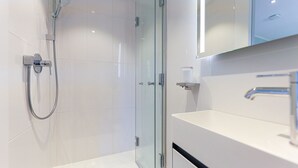 A modern bathroom with a glass shower enclosure, a white sink, and a mirror above the sink. - Palenque - Apartment Palenque (Sylt-Ost)