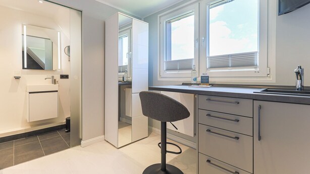 A modern kitchen with a built-in oven, a sink, and a window with blinds. - Palenque - Apartment Palenque (Sylt-Ost)