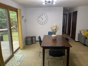 Un coin repas avec une table en bois, des chaises, une horloge et un vase rempli de fleurs.