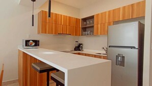 Een moderne keuken met houten kastjes, een wit aanrecht, een ingebouwde magnetron, een koffiezetapparaat en een roestvrijstalen koelkast.