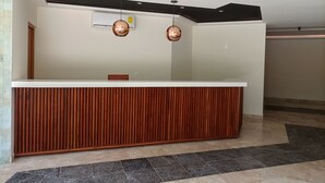 Een receptiebalie met een houten paneelstructuur, een plafond met inbouwspots, en een airconditioner bevestigd aan de muur.