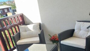 Een patio met rieten meubilair, waaronder twee banken en een bijzettafeltje.