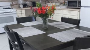 Een moderne keuken met witte kasten, een donker houten tafel en vier stoelen.
