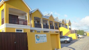 Een geel gebouw met meerdere balkons en een bord met daarop Ocean Gaze Apartments & Condos.