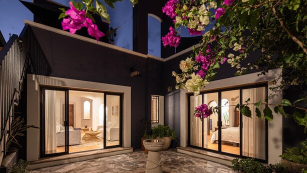 A courtyard with a central fountain, potted plants, and two glass doors leading to interior spaces.