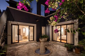 A courtyard with a central fountain, potted plants, and two glass doors leading to interior spaces. - Rooftop Terrace Views! Stylish 4BR Hacienda (San Miguel de Allende)