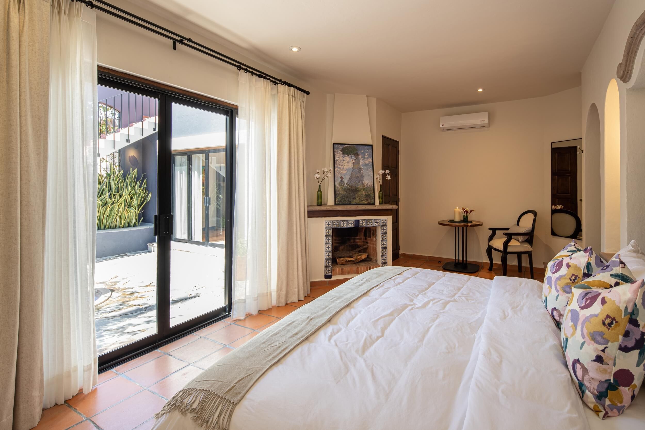 Un dormitorio con una cama grande, una chimenea, una mesa de comedor y vistas al exterior.