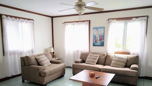 Ein Wohnzimmer mit zwei Sofas, einem Couchtisch und einem Deckenventilator.