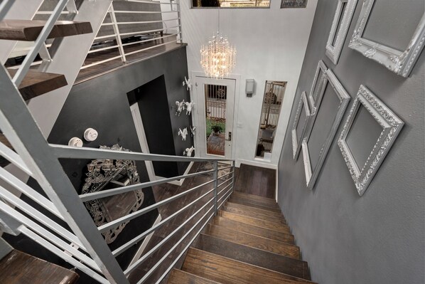 Un escalier moderne avec une rampe en métal, des marches en bois et un lustre.