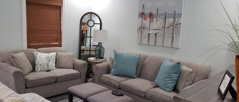 A living room with two sofas, a side table, a lamp, and a painting on the wall.