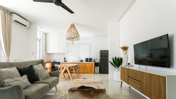 Uma sala de estar moderna com sofá, um apoio para os pés e uma TV de tela plana.