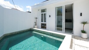 Uma casa moderna com piscina, fachada branca e portas de vidro deslizantes que dão para um espaço de varanda.