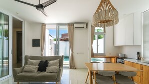 Uma sala de estar moderna com sofá, mesa de jantar e área de cozinha.