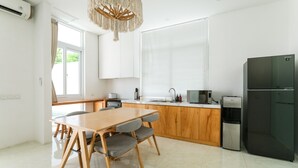 Cozinha moderna com mesa e cadeiras de madeira, uma geladeira preta e uma janela com persianas.