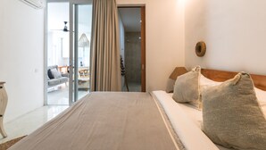 Quarto de hotel com cama, cabeceira de madeira e uma janela grande com cortinas.