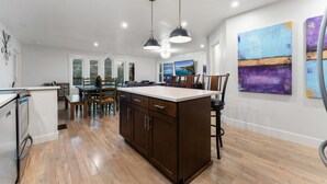 A spacious kitchen with a central island, wooden cabinets, and pendant lighting.