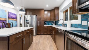 A modern kitchen with wooden cabinets, stainless steel appliances, and a large island.