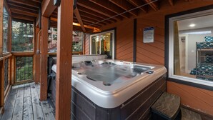 A wooden deck with a hot tub, a window with a view of a building, and a sign on the wall.