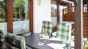 A patio with a table and chairs, a potted plant, and a bottle of champagne.