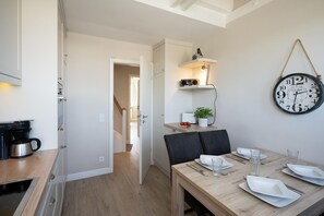 Une cuisine moderne équipée d’une machine à café, d’une table à manger pour deux personnes et d’une horloge murale.