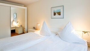 A hotel room with a bed, bedside lamps, a nightstand, and a framed picture on the wall. - Risgap - Schmidtpott - Cozy 3-room apartment for 4 persons with terrace (Wenningstedt-Braderup (Sylt))