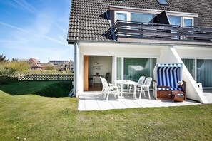 Une maison moderne dotée d’un patio, d’un coin repas et d’une chaise de plage à rayures.