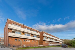 A multi-story building with a brick facade, balconies, and a parking area. - Seestern - Bright app. for 2 pers. - Balcony, parking space, WLAN. Pets (Wenningstedt-Braderup (Sylt))