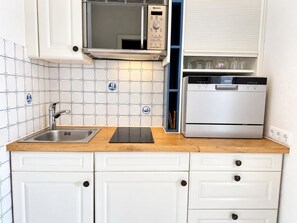 A kitchen with a stainless steel sink, a microwave, and a dishwasher. - Seestern - Bright app. for 2 pers. - Balcony, parking space, WLAN. Pets (Wenningstedt-Braderup (Sylt))