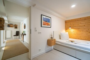 A modern bedroom with a wooden headboard, a bedside table, and a framed picture on the wall.