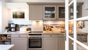 A modern kitchen with a built-in oven, a coffee maker, and a breakfast bar.