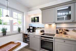 Eine moderne Küche mit Backofen, Kaffeemaschine und einem Fenster mit Topfpflanzen.