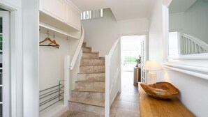 A staircase with a handrail, a wooden bench, and a hanging coat rack.
