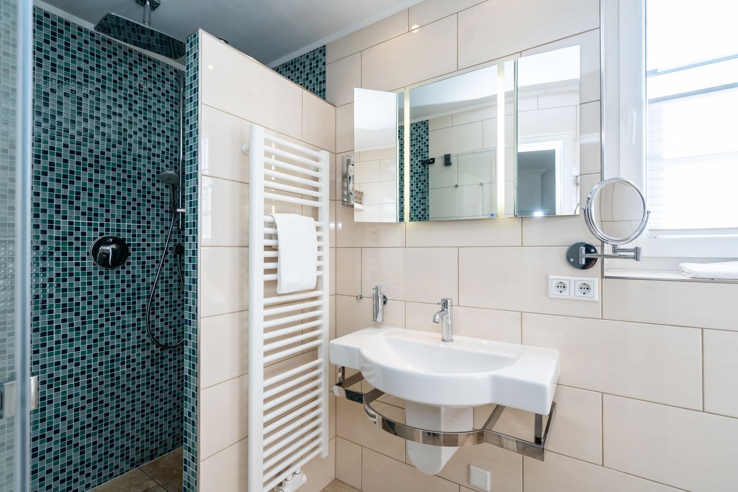 Un bagno moderno con box doccia in vetro, lavandino bianco e rubinetteria cromata, e uno specchio grande sopra il lavandino.