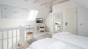 A bedroom with a bed, a desk, a chair, a mirror, and a window.