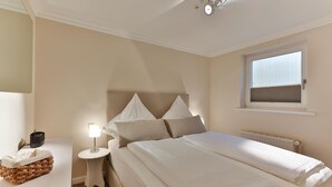 A bedroom with a bed, bedside tables, a lamp, a window, and a radiator.