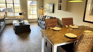 A dining area with a wooden table set for four, surrounded by wicker chairs.